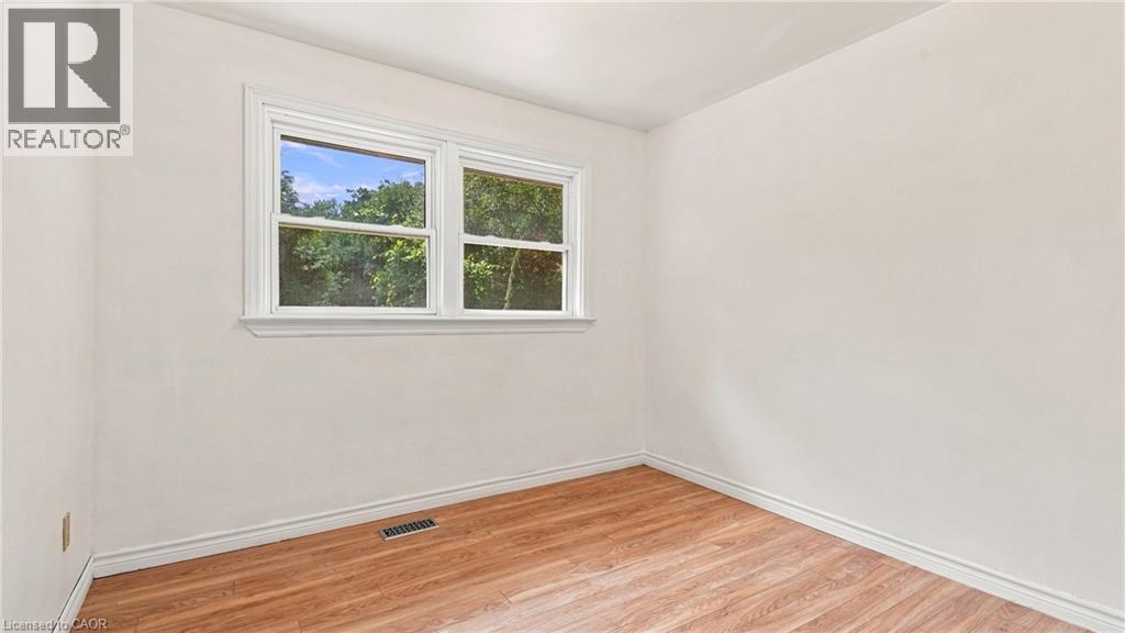 Room featuring light-colored walls, wood-finish flooring, white baseboards, and a white-framed window - 524 Dorval Drive, Ancaster, ON - Indoor Photo Showing Other Room