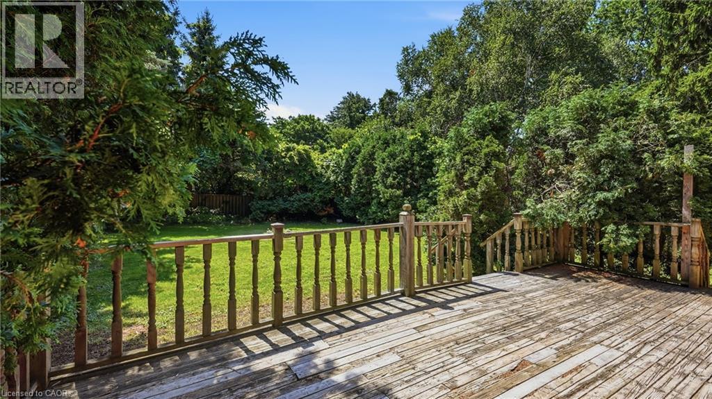 Spacious wood deck with turned baluster railing and integrated steps, overlooking a verdant lawn and mature trees - 524 Dorval Drive, Ancaster, ON - Outdoor