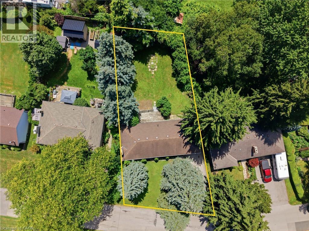 Expansive property featuring a brown shingle roof, mature perimeter trees, a large grassy backyard, and a paved driveway - 524 Dorval Drive, Ancaster, ON - Outdoor With View