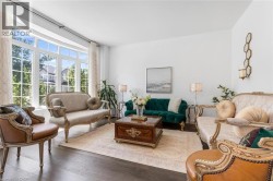 Spacious living area featuring expansive bay windows, dark wood-finish flooring, white walls, and a recessed ceiling - 