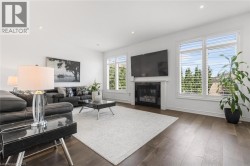 Living area featuring dark wood-finish flooring, white walls, and a fireplace with a dark surround and white mantel - 