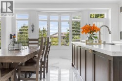 Kitchen island featuring a light-toned countertop, dark wood-finish cabinetry with brass-toned hardware, and an integrated sink with a gooseneck faucet - 