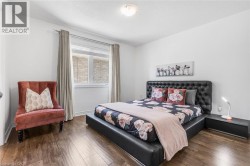 Expansive room featuring wood-finish flooring, a contemporary window with drapes, and a flush-mount ceiling light - 