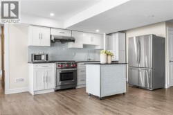 Kitchen featuring light wood-finish flooring, white cabinetry, dark countertops, and a light blue tiled backsplash - 