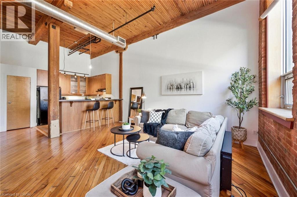 Open-concept living space featuring exposed wood beams, high wood plank ceilings, and polished wood flooring - 26 Ontario Street Unit# 127, Guelph, ON - Indoor Photo Showing Living Room