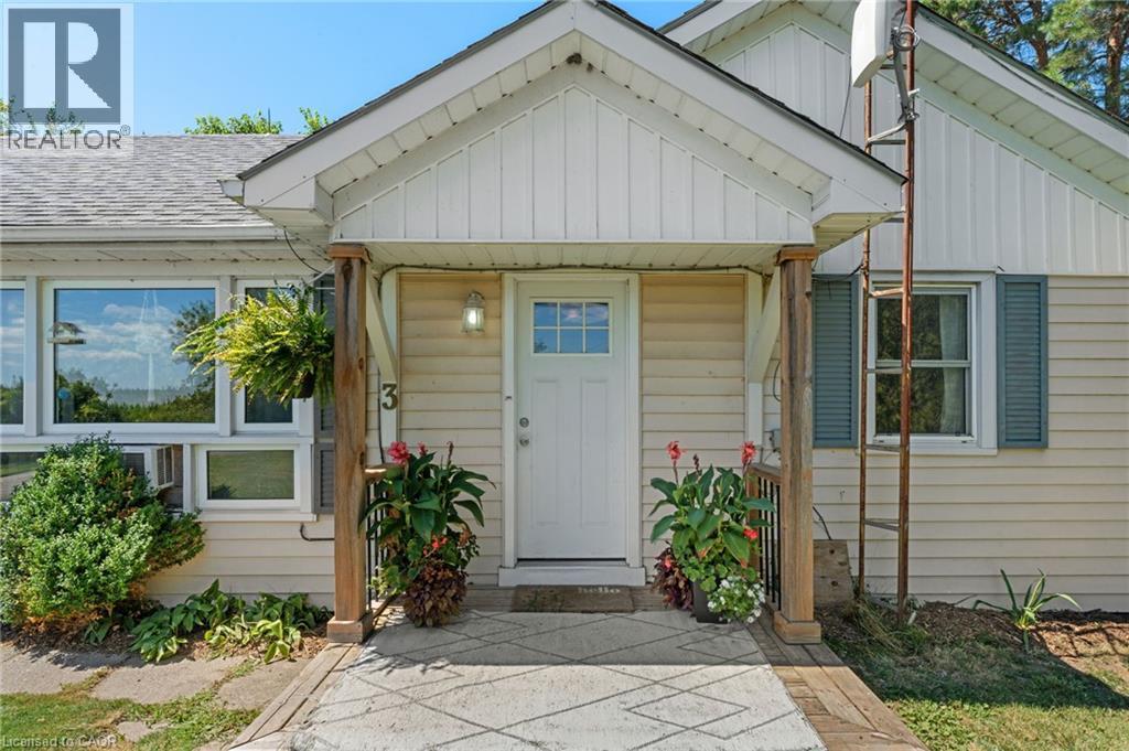 Cream-colored siding exterior featuring a white paneled front door, wood-finish porch columns, and a gabled entryway - 3 Bousfield Lane, Jarvis, ON - Outdoor With Exterior