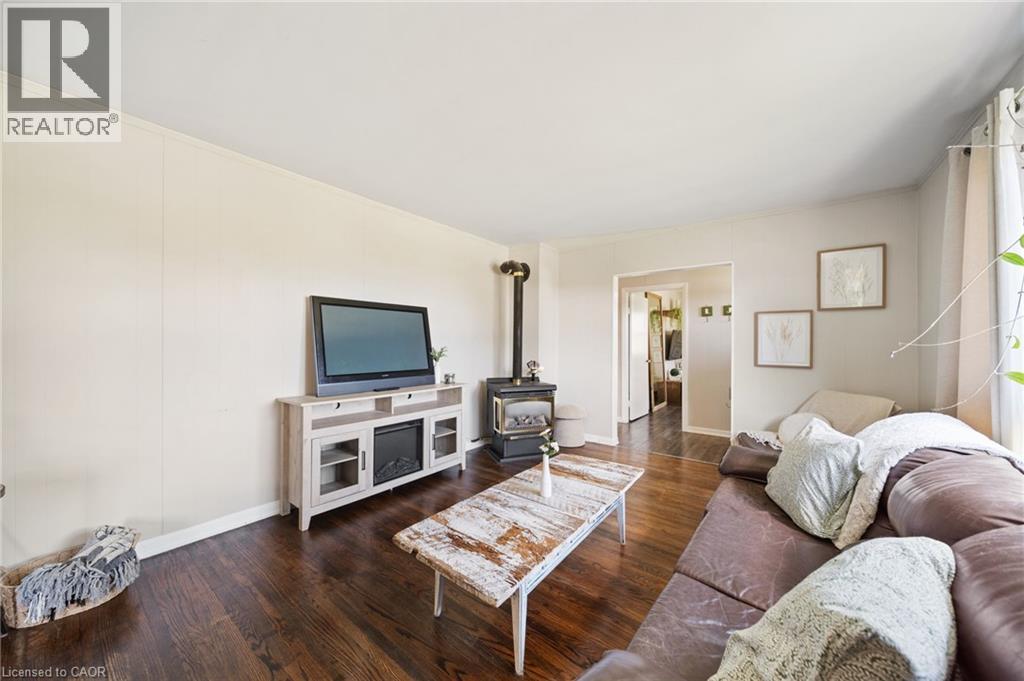 Living area featuring dark wood-finish flooring, a built-in wood-burning stove, and light-toned wall paneling - 3 Bousfield Lane, Jarvis, ON - Indoor Photo Showing Living Room