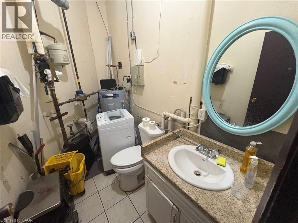 Compact utility space with a built-in vanity featuring a speckled countertop and an oval sink - 209 Lexington Road Unit# F, Waterloo, ON