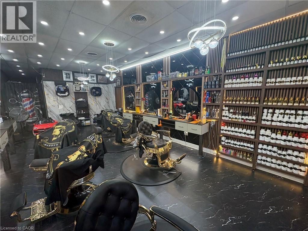 Barber shop interior featuring multiple styling stations with upholstered chairs, black and white marble-look flooring, and recessed lighting - 209 Lexington Road Unit# F, Waterloo, ON