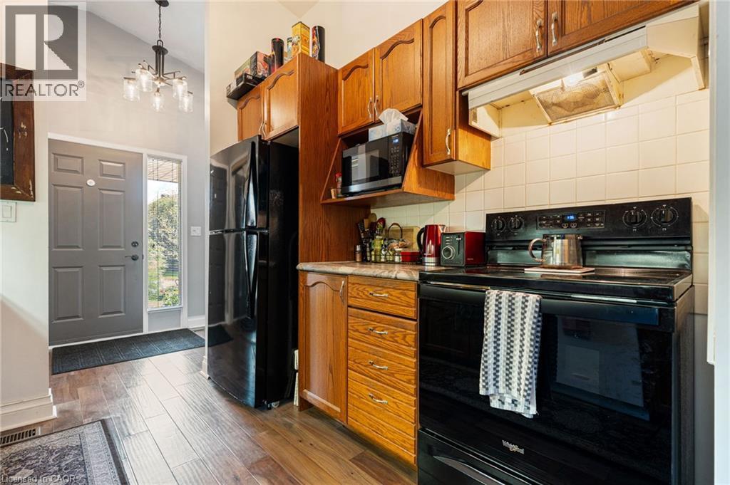 Compact kitchen featuring wood-finish cabinetry and a black appliance suite - 2 Hampton Court, Port Dover, ON - Indoor Photo Showing Kitchen