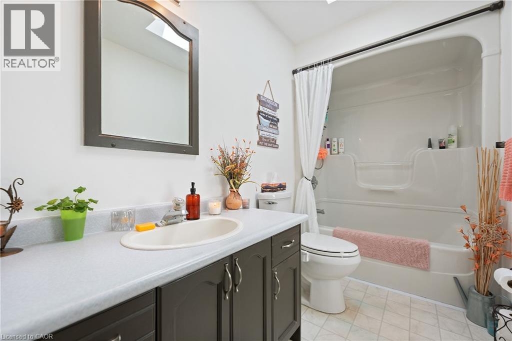 Bathroom featuring a dark wood-finish vanity with an integrated sink, a white countertop, and an arched mirror - 2 Hampton Court, Port Dover, ON - Indoor Photo Showing Bathroom