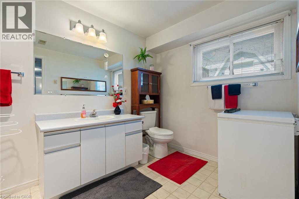 Bathroom featuring a white vanity with integrated sink, rectangular mirror, and three-light fixture - 2 Hampton Court, Port Dover, ON - Indoor Photo Showing Bathroom