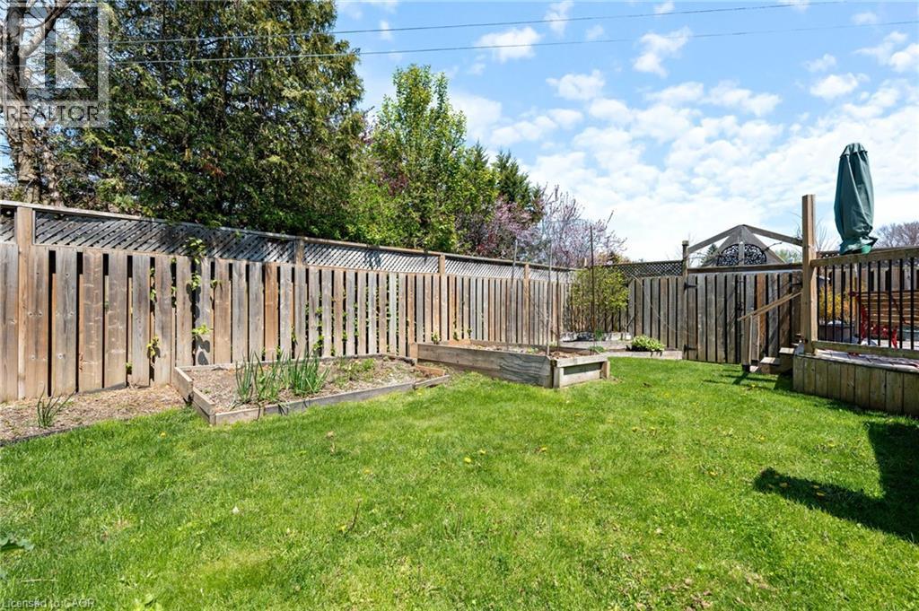 Expansive backyard featuring a manicured lawn, raised garden beds, and a wood privacy fence - 2 Hampton Court, Port Dover, ON - Outdoor