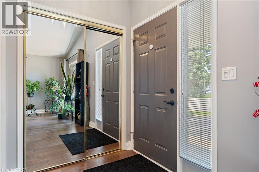 Entryway featuring a paneled door with matte black hardware, a sidelight with blinds, and wood-finish flooring - 2 Hampton Court, Port Dover, ON - Indoor Photo Showing Other Room
