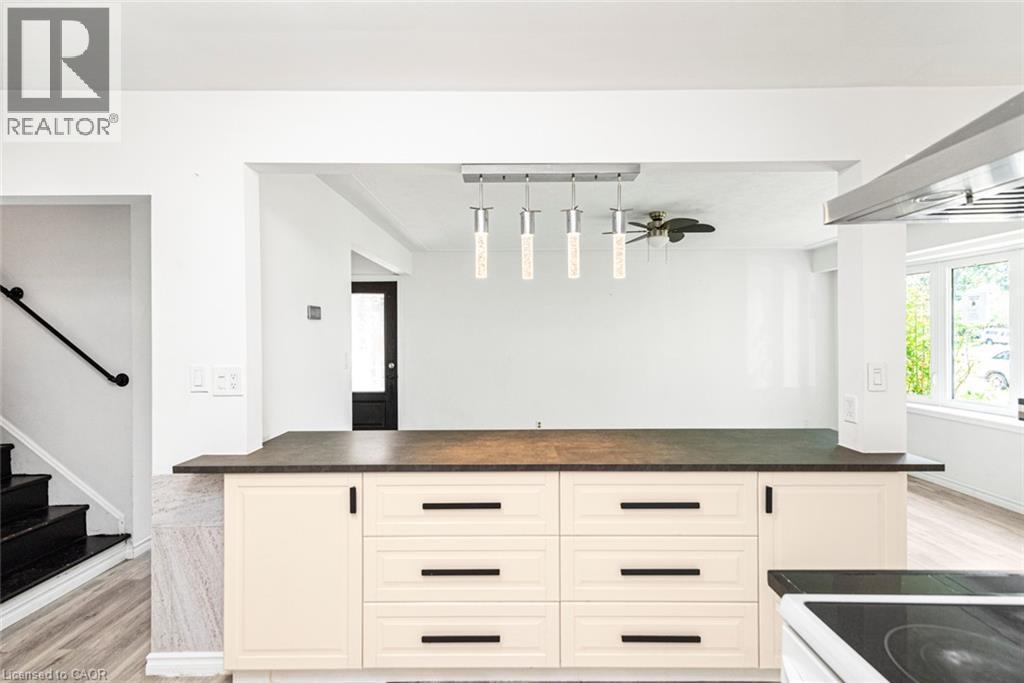 Kitchen island featuring light-toned cabinetry with dark hardware and a dark countertop - 100 Mountain Avenue N, Hamilton, ON - Indoor