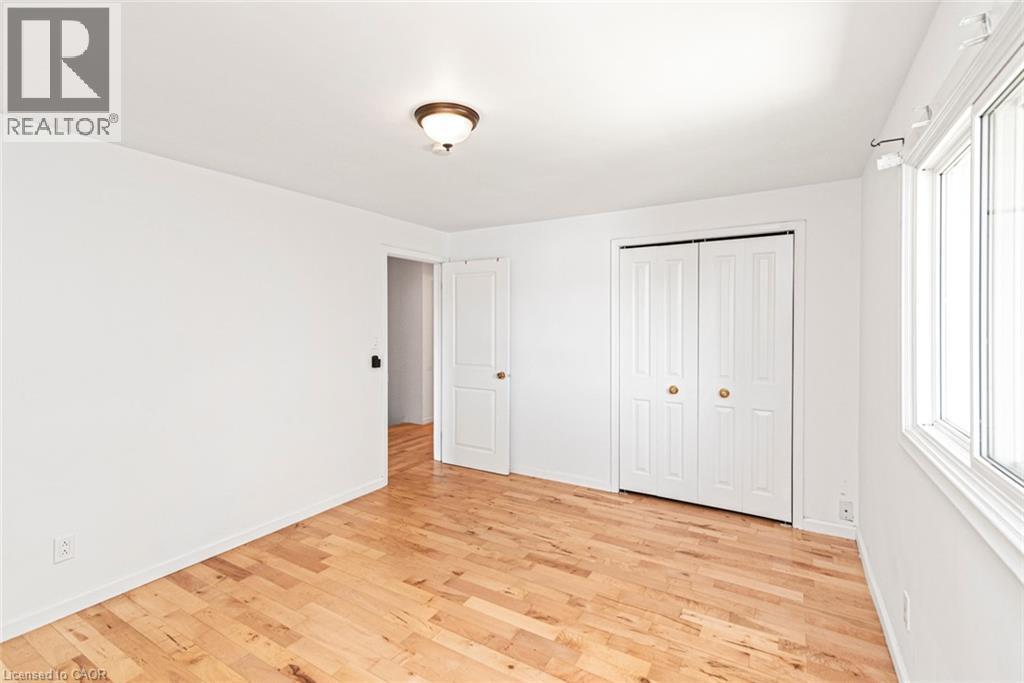 Bright interior space featuring wood-finish flooring, white walls, and a ceiling-mounted light fixture - 100 Mountain Avenue N, Hamilton, ON - Indoor Photo Showing Other Room