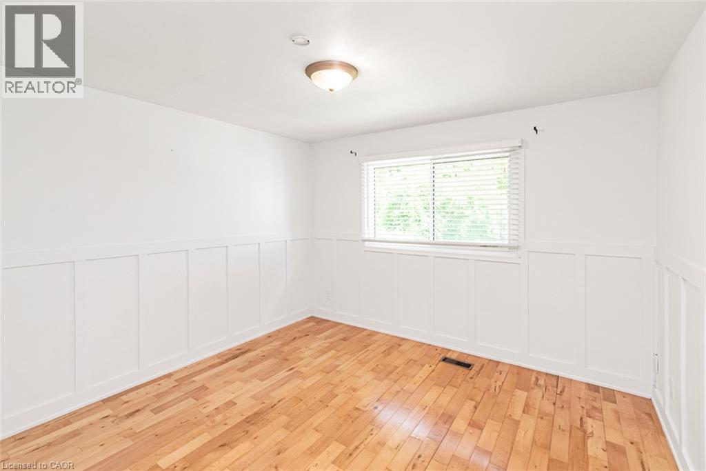 Room featuring wood-finish flooring, white board and batten wall detailing, a window with blinds, and a flush-mount ceiling light fixture - 100 Mountain Avenue N, Hamilton, ON - Indoor Photo Showing Other Room