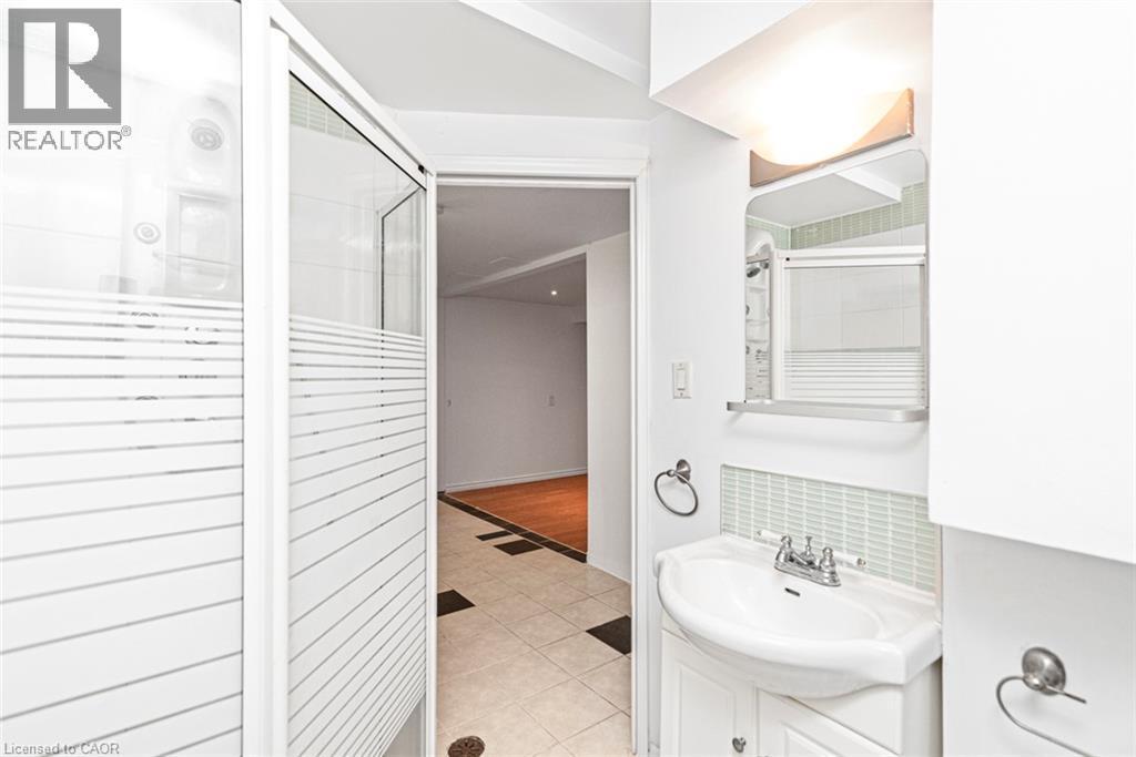 Spa-inspired primary bathroom featuring a frameless glass-enclosed shower with horizontal tile detailing, pedestal sink with chrome fixtures, recessed lighting, and neutral tile flooring throughout - 100 Mountain Avenue N, Hamilton, ON - Indoor Photo Showing Bathroom