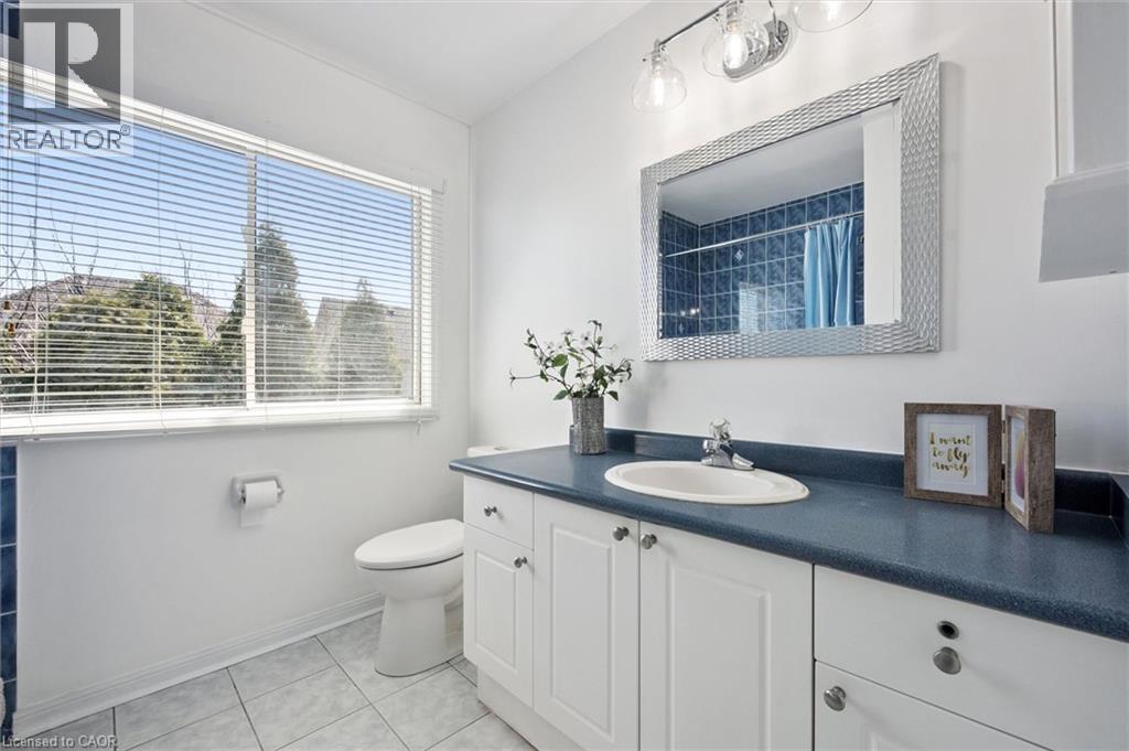 Bathroom featuring a broad window, white vanity with cabinet storage, integrated sink, and a blue countertop - 5147 Ravine Crescent, Burlington, ON - Indoor Photo Showing Bathroom