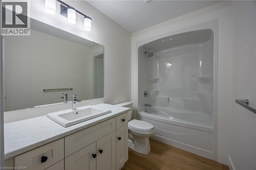 Bathroom featuring a white vanity with a rectangular sink, a light-toned countertop, and wood-finish flooring - 111 Amber Street, Waterford, ON - Indoor Photo Showing Bathroom