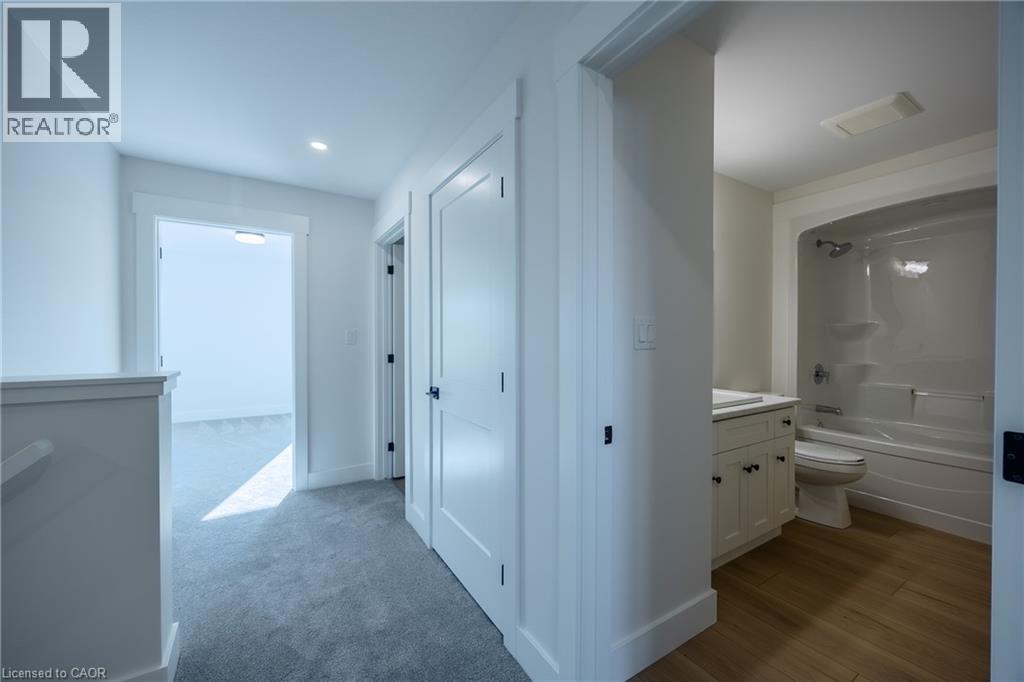Hallway with light gray carpeting, white trim, and white doors - 111 Amber Street, Waterford, ON - Indoor Photo Showing Bathroom