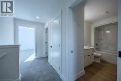 Hallway with light gray carpeting, white trim, and white doors -