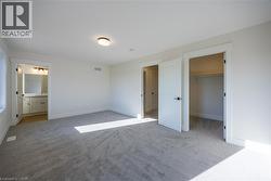 Spacious room featuring light gray carpeting, neutral wall finishes, and a contemporary ceiling light fixture -