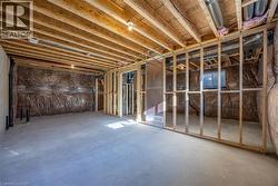 Unfinished lower level featuring exposed wood joists, concrete flooring, perimeter insulation, framed interior walls, and an egress window -