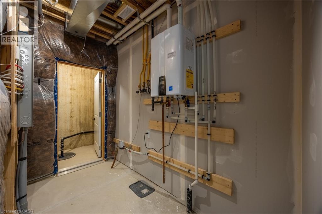 Utility area featuring a wall-mounted water heater, exposed overhead ductwork, and a visible electrical panel - 111 Amber Street, Waterford, ON - Indoor Photo Showing Basement
