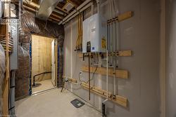 Utility area featuring a wall-mounted water heater, exposed overhead ductwork, and a visible electrical panel -