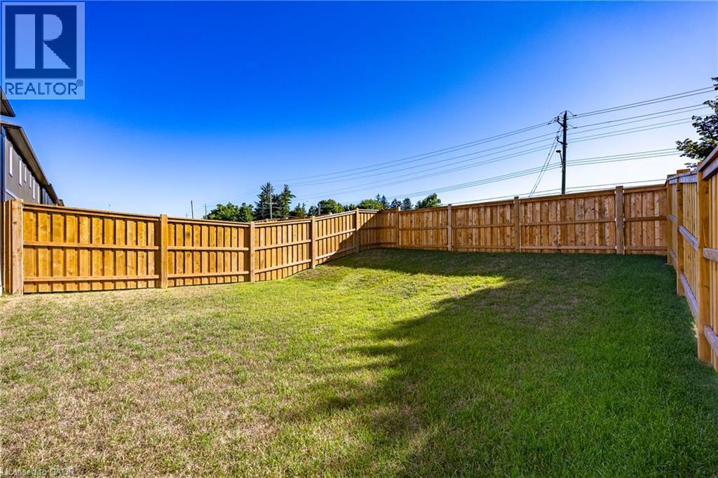 Expansive backyard featuring a full perimeter wood privacy fence and a verdant lawn - 111 Amber Street, Waterford, ON - Outdoor
