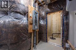 Utility space featuring insulation, an electrical panel, and a sump pump -