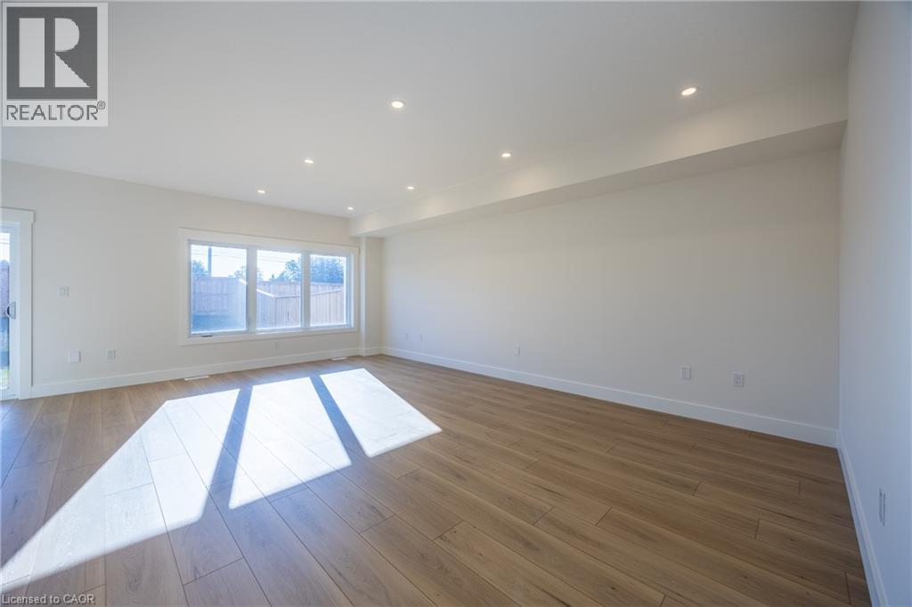 Spacious room featuring wood-finish flooring, recessed lighting, expansive windows, white baseboards, and a sliding glass door - 111 Amber Street, Waterford, ON - Indoor Photo Showing Other Room