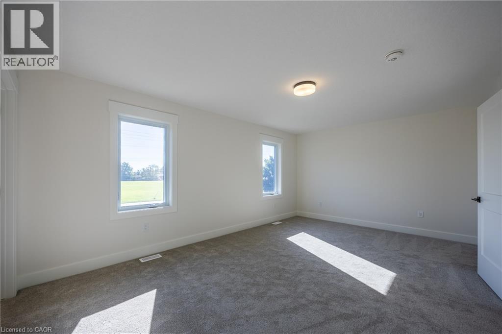 Spacious interior room with two windows, light gray carpet, white walls, and a flush-mount ceiling light fixture - 115 Amber Street, Waterford, ON - Indoor Photo Showing Other Room