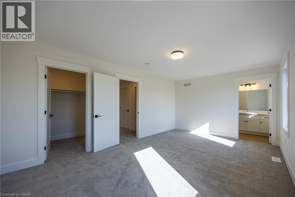Carpeted room featuring a ceiling-mounted light fixture, white trim, and a window - 115 Amber Street, Waterford, ON - Indoor Photo Showing Other Room