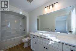 Bathroom featuring a white vanity with shaker-style cabinetry, a rectangular undermount sink, and a white countertop -