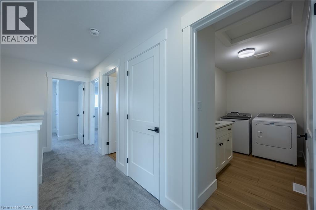 Dedicated laundry area featuring wood-finish flooring and a built-in vanity with countertop - 115 Amber Street, Waterford, ON - Indoor Photo Showing Laundry Room