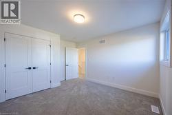 Carpeted room featuring a double-door closet with dark hardware, a single window, and a flush-mount ceiling light fixture -