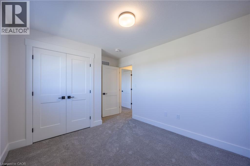 Neutral-toned carpet flooring and white walls create a versatile interior space - 115 Amber Street, Waterford, ON - Indoor Photo Showing Other Room