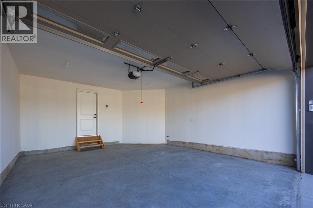 Spacious garage featuring a concrete floor, white painted walls, and a finished ceiling with an automatic opener - 115 Amber Street, Waterford, ON - Indoor Photo Showing Garage