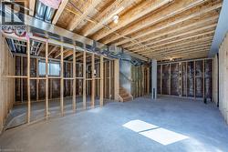 Unfinished basement space featuring exposed wood framing, concrete flooring, visible HVAC ductwork, and insulation -