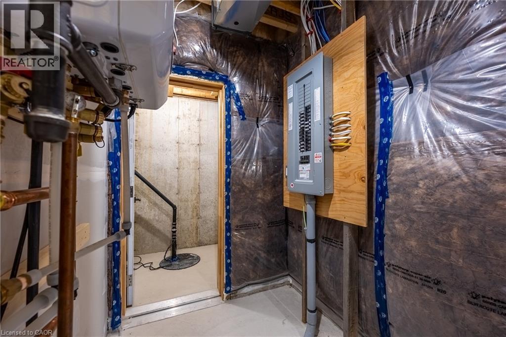 Mechanical room featuring a contemporary tankless water heater, a well-organized electrical panel mounted on a wood board, and visible plumbing lines - 115 Amber Street, Waterford, ON - Indoor