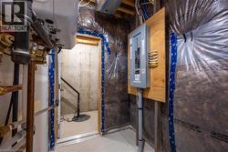 Mechanical room featuring a contemporary tankless water heater, a well-organized electrical panel mounted on a wood board, and visible plumbing lines -