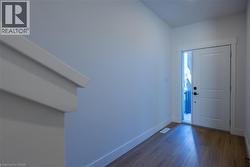 Entryway featuring wood-finish flooring, white baseboards, a solid white door with black hardware, and a sidelight window -