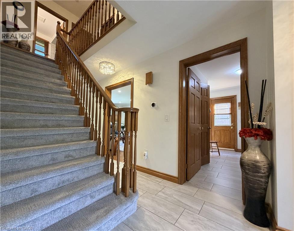 Carpeted staircase to the upper level featuring wooden newel posts and spindles. Door to main floor lauundy at right. - 7 Mann Avenue, Simcoe, ON - Indoor Photo Showing Other Room