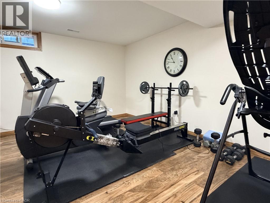 Dedicated fitness area featuring wood-finish flooring, a flush-mount ceiling light, and a horizontal window with wood trim - 7 Mann Avenue, Simcoe, ON - Indoor Photo Showing Gym Room