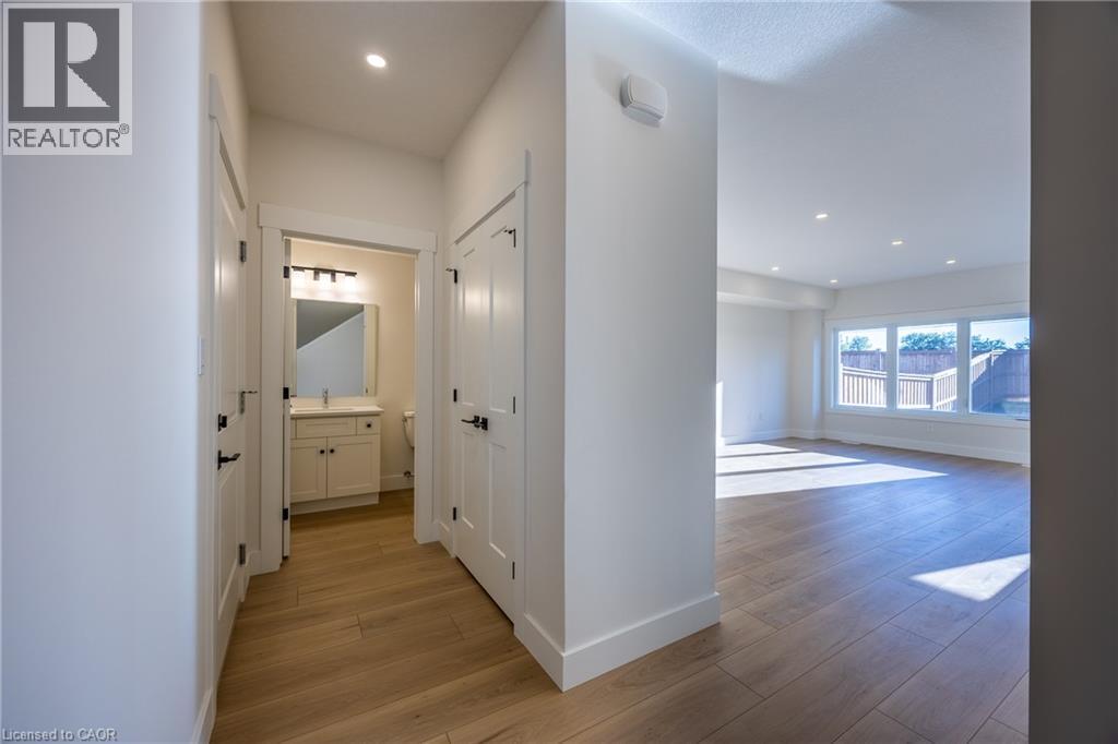 Entryway featuring wood-finish flooring, white trim, recessed lighting, and a powder room with a vanity, rectangular sink, and wall-mounted light fixture - 107 Amber Street, Waterford, ON - Indoor Photo Showing Other Room