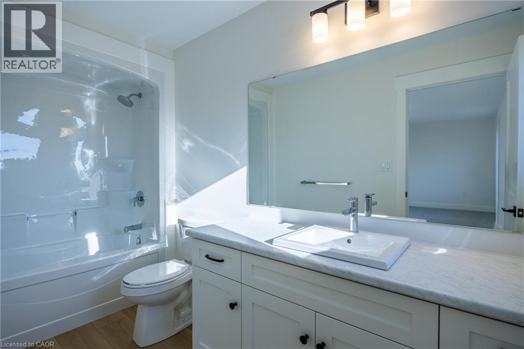 Bathroom featuring a white vanity with recessed panel cabinetry, an integrated sink, and a light-toned countertop - 107 Amber Street, Waterford, ON - Indoor Photo Showing Bathroom