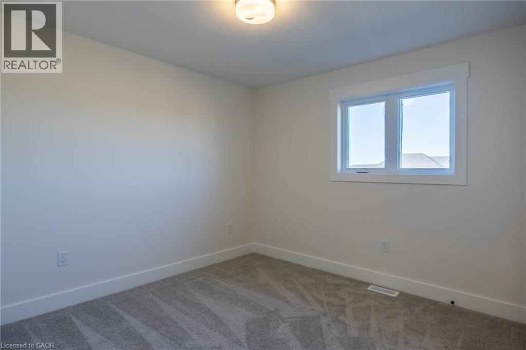 Neutral-toned room featuring a double-pane window with white trim, gray carpet flooring, and white baseboards - 107 Amber Street, Waterford, ON - Indoor Photo Showing Other Room