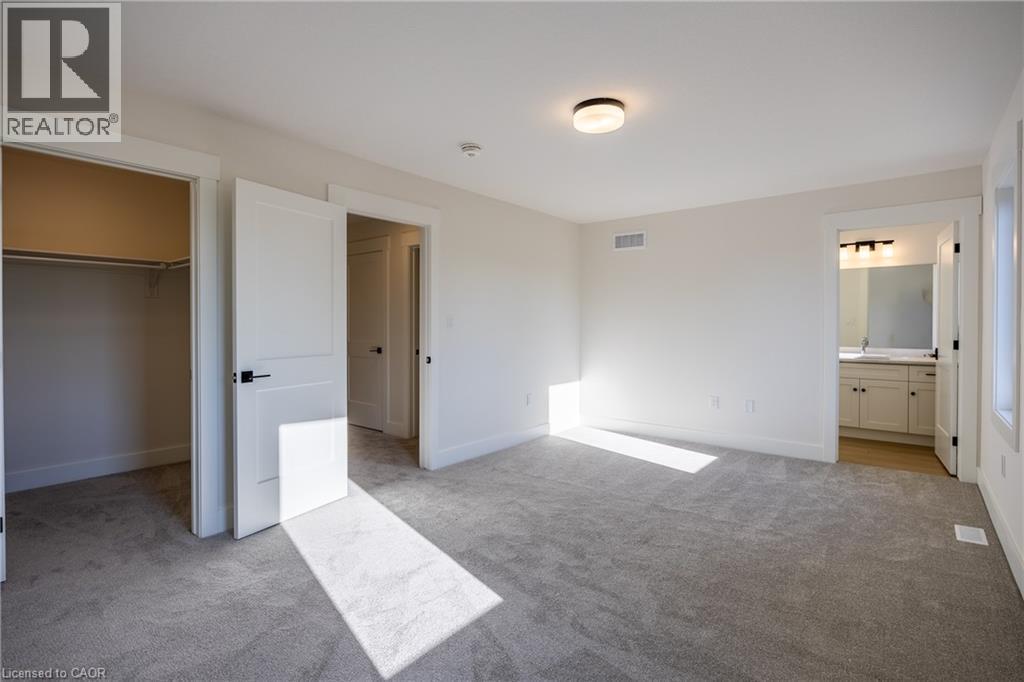 Spacious bedroom with light gray carpeting, crisp white walls, and a recessed closet - 107 Amber Street, Waterford, ON - Indoor Photo Showing Other Room